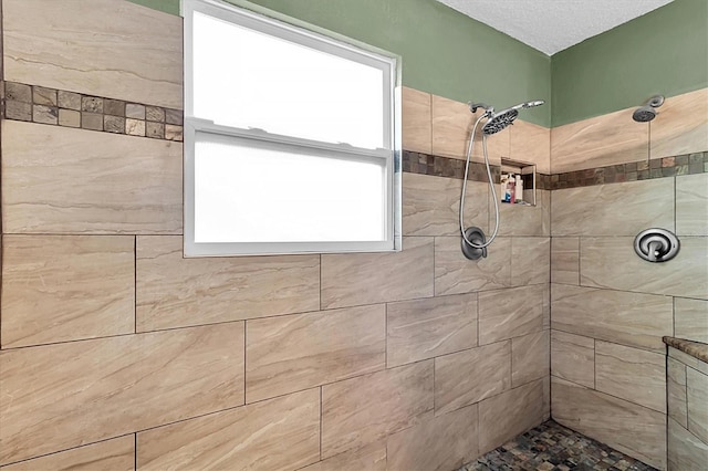 bathroom with a textured ceiling and tiled shower