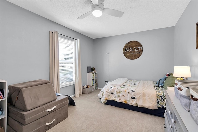 bedroom featuring ceiling fan, light colored carpet, and a textured ceiling