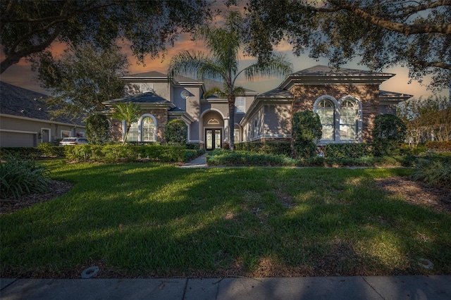 mediterranean / spanish home with a lawn and french doors