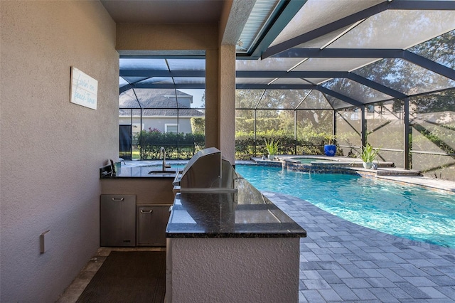 view of swimming pool with a lanai, an in ground hot tub, sink, and exterior kitchen