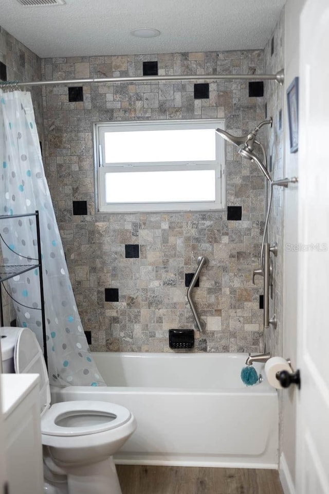 full bathroom with vanity, shower / bath combination with curtain, a textured ceiling, and toilet