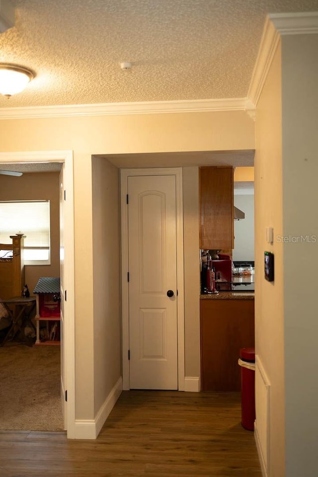 corridor featuring wood-type flooring, a textured ceiling, and ornamental molding