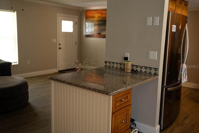 kitchen with stainless steel fridge, dark stone counters, dark hardwood / wood-style floors, and crown molding