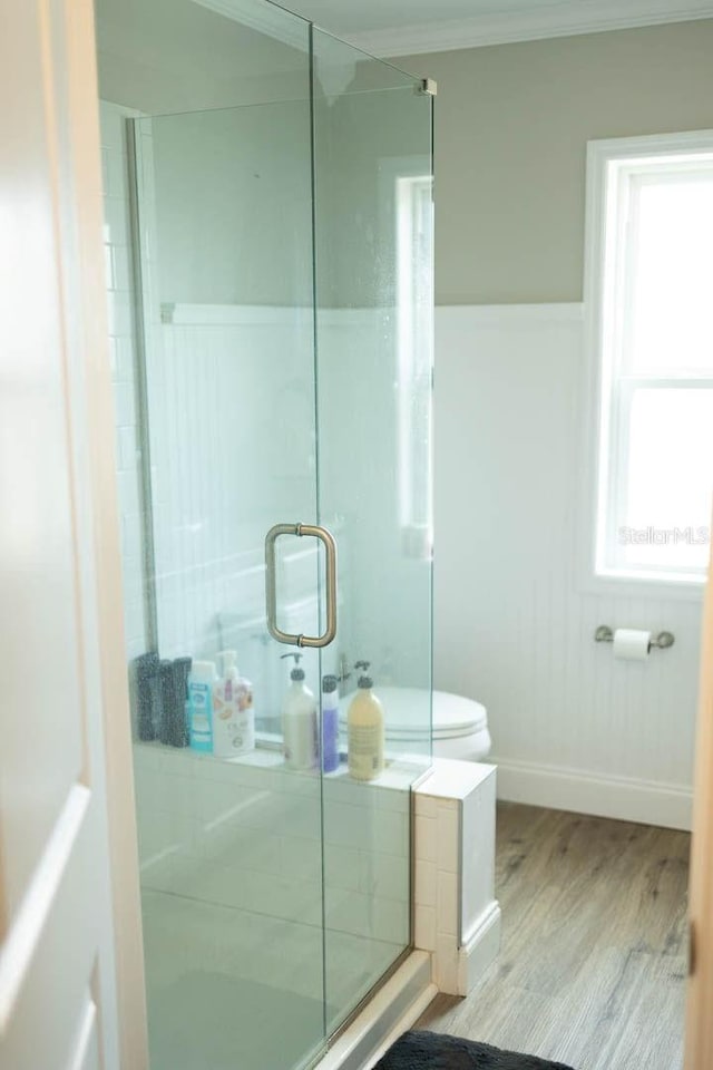 bathroom with hardwood / wood-style flooring, toilet, crown molding, and walk in shower