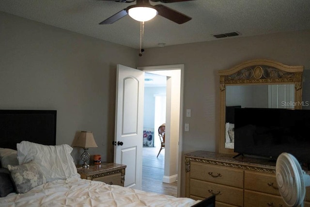 bedroom with ceiling fan, light wood-type flooring, and a textured ceiling