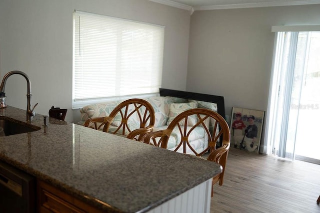 dining space with sink, wood-type flooring, and ornamental molding