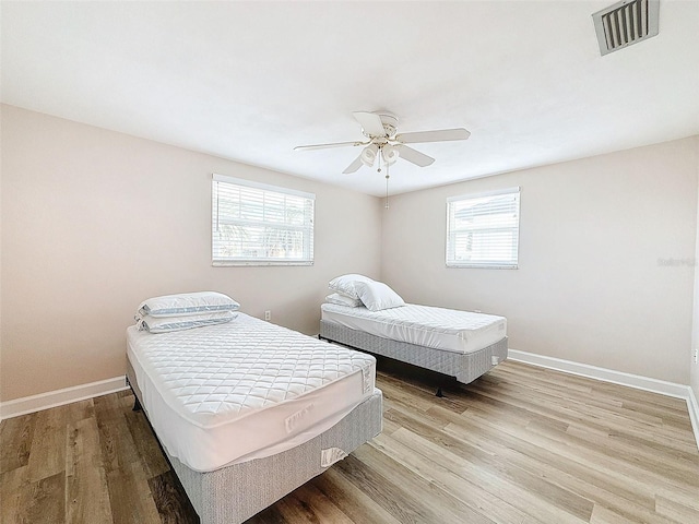 bedroom featuring ceiling fan, light wood-type flooring, and multiple windows