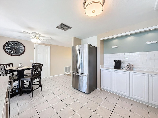 kitchen featuring light tile patterned flooring, ceiling fan, white cabinetry, and stainless steel fridge