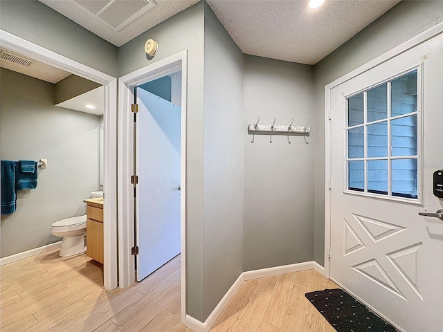 mudroom with light wood-type flooring and a textured ceiling