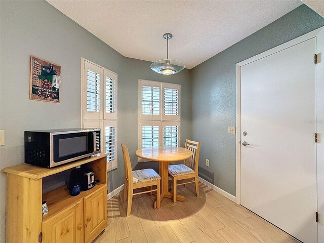 dining room featuring light wood-type flooring and a textured ceiling