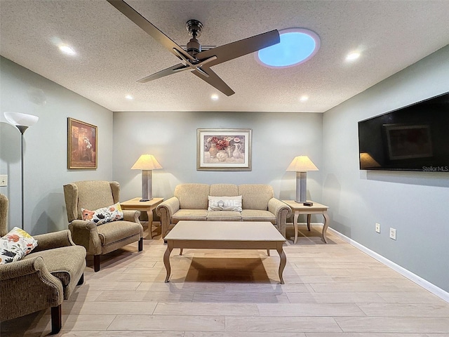 living room featuring ceiling fan, light hardwood / wood-style floors, and a textured ceiling