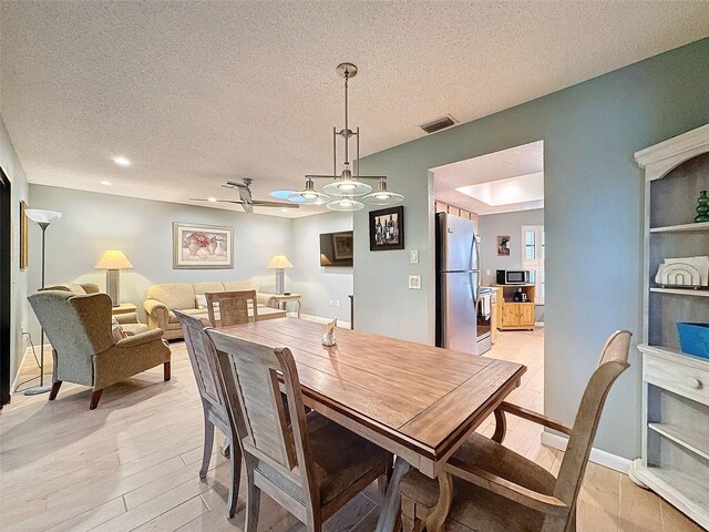 dining room featuring light wood-type flooring and a textured ceiling