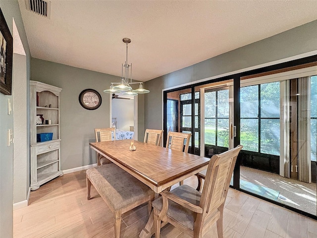 dining room with a textured ceiling and light hardwood / wood-style flooring