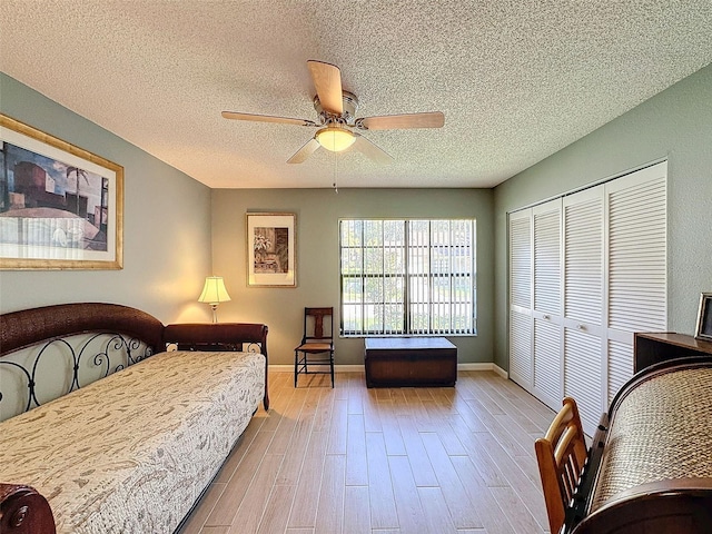 bedroom featuring a textured ceiling, a closet, light hardwood / wood-style flooring, and ceiling fan