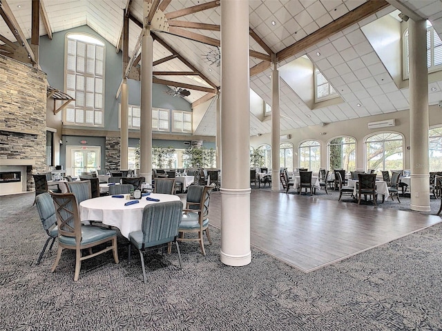 dining area featuring high vaulted ceiling, dark hardwood / wood-style floors, a fireplace, beamed ceiling, and decorative columns