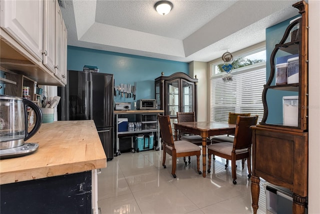 tiled dining room featuring a raised ceiling and a textured ceiling