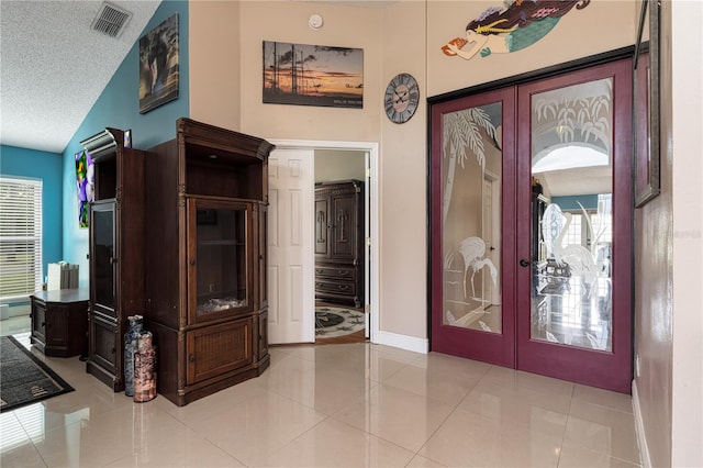 tiled foyer entrance featuring french doors, a textured ceiling, and vaulted ceiling