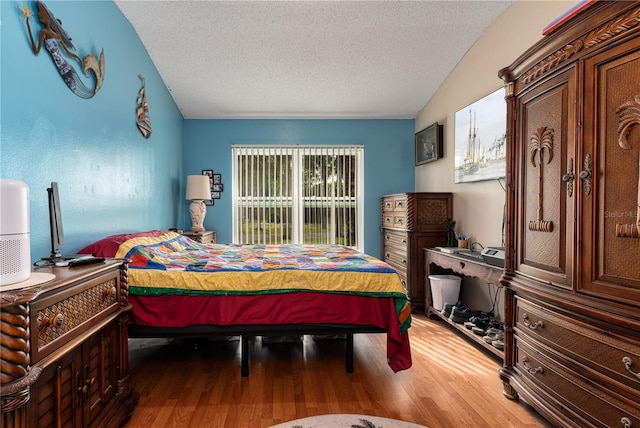 bedroom featuring a textured ceiling, vaulted ceiling, and hardwood / wood-style flooring