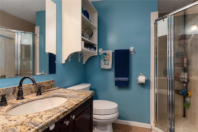 bathroom with tile patterned floors, vanity, a shower with shower door, and toilet