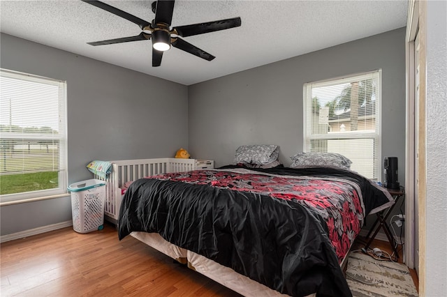 bedroom with multiple windows, ceiling fan, a textured ceiling, and hardwood / wood-style flooring