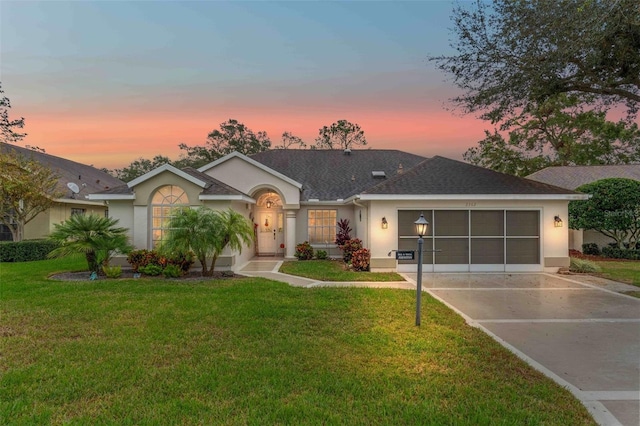 ranch-style home with a garage and a yard