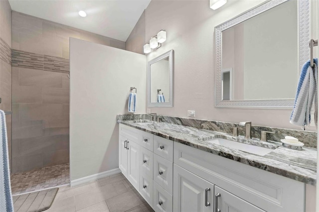 bathroom featuring tile patterned floors, vanity, a tile shower, and vaulted ceiling