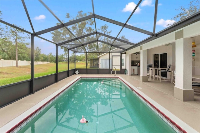 view of pool with a patio, glass enclosure, and a lawn