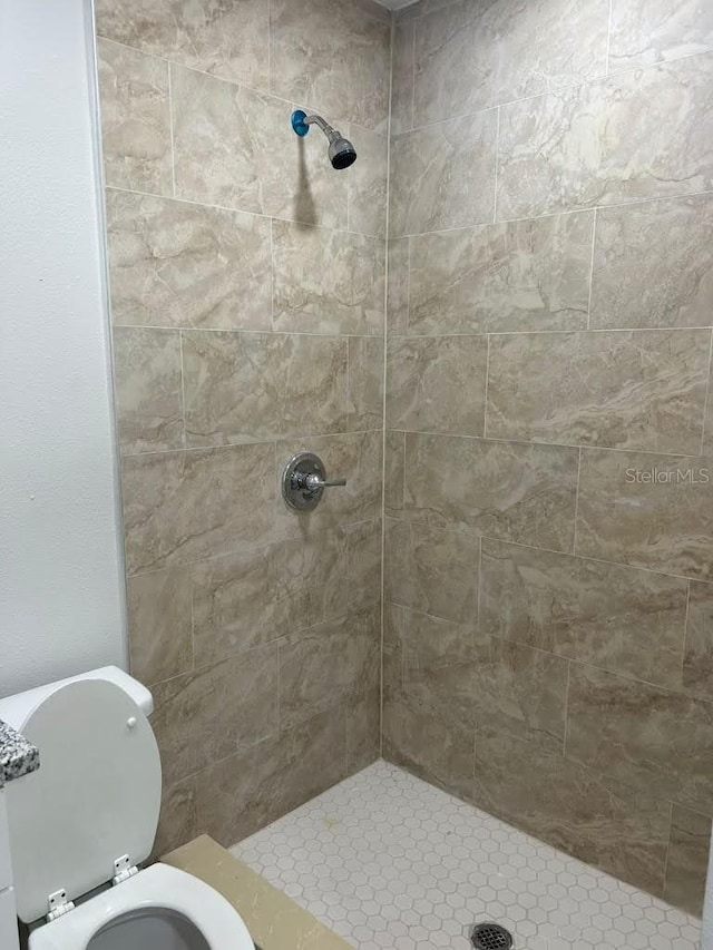 bathroom featuring tiled shower and toilet