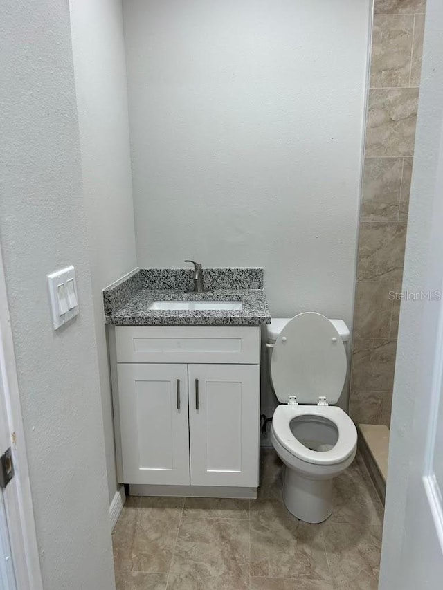 bathroom featuring toilet, a shower, and vanity