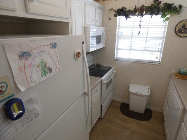 kitchen featuring white cabinets, wood-type flooring, and white appliances