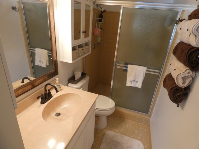 bathroom featuring tile patterned floors, vanity, toilet, and a shower with door