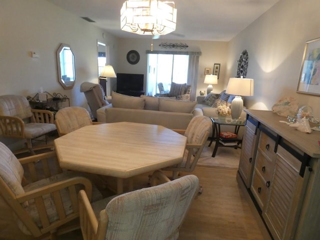 dining area featuring light wood-type flooring and a notable chandelier