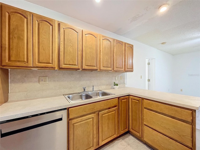 kitchen featuring sink, stainless steel dishwasher, light tile patterned floors, a textured ceiling, and kitchen peninsula