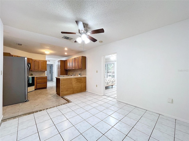 kitchen featuring ceiling fan, light tile patterned floors, a textured ceiling, appliances with stainless steel finishes, and kitchen peninsula