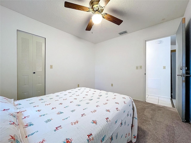 bedroom featuring a textured ceiling, carpet floors, a closet, and ceiling fan