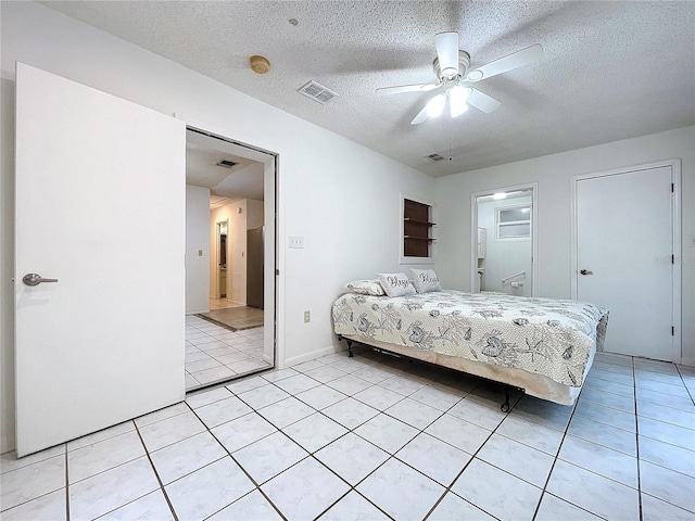 bedroom featuring ceiling fan, light tile patterned flooring, a textured ceiling, and ensuite bath