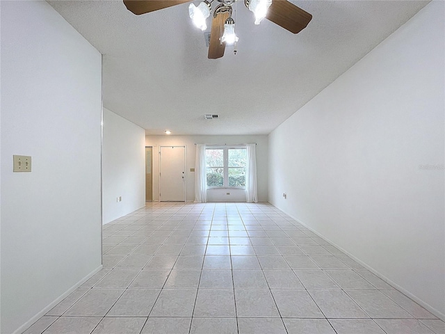 tiled empty room featuring ceiling fan and a textured ceiling