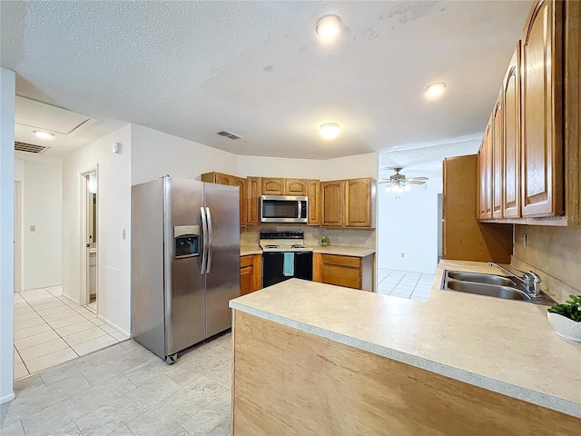 kitchen featuring ceiling fan, sink, kitchen peninsula, light tile patterned flooring, and appliances with stainless steel finishes