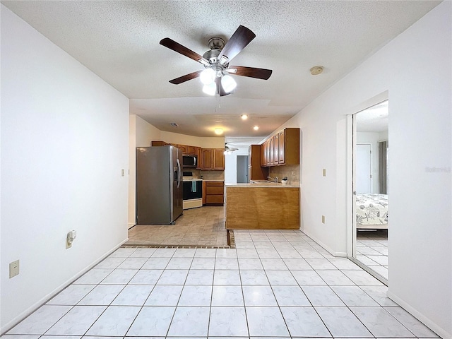 kitchen with kitchen peninsula, appliances with stainless steel finishes, backsplash, a textured ceiling, and ceiling fan