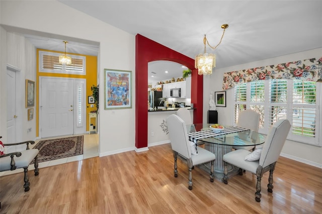 dining area featuring light hardwood / wood-style floors, vaulted ceiling, sink, and an inviting chandelier