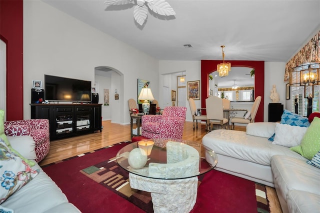 living room featuring hardwood / wood-style flooring, ceiling fan with notable chandelier, and lofted ceiling