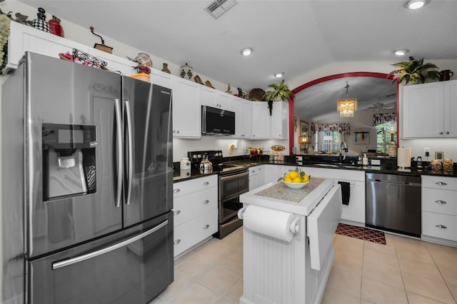 kitchen featuring white cabinets, decorative light fixtures, appliances with stainless steel finishes, and vaulted ceiling