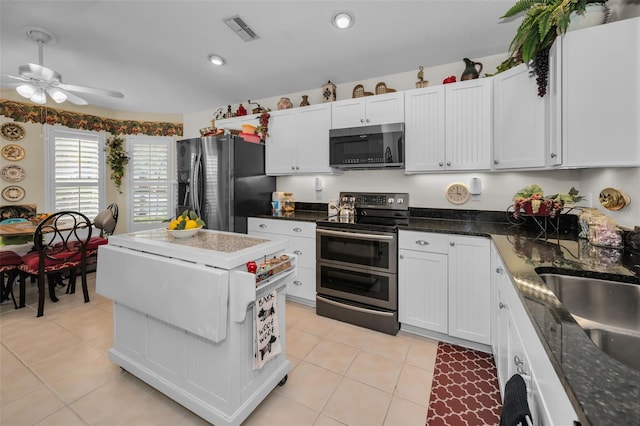 kitchen with light tile patterned flooring, white cabinetry, stainless steel appliances, and dark stone counters