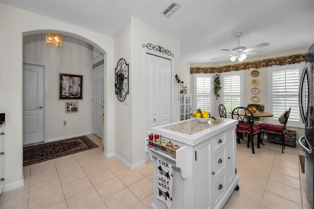 kitchen featuring ceiling fan with notable chandelier, white cabinetry, a kitchen island, and light tile patterned flooring