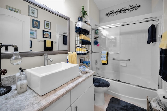 full bathroom with tile patterned floors, vanity, bath / shower combo with glass door, and toilet