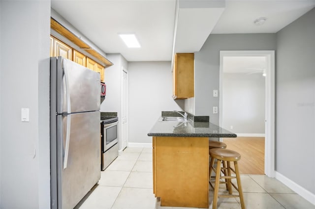 kitchen featuring kitchen peninsula, stainless steel fridge, stove, a breakfast bar, and light tile patterned floors