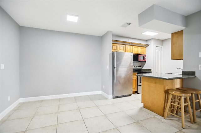 kitchen with a breakfast bar area, kitchen peninsula, light tile patterned flooring, and appliances with stainless steel finishes