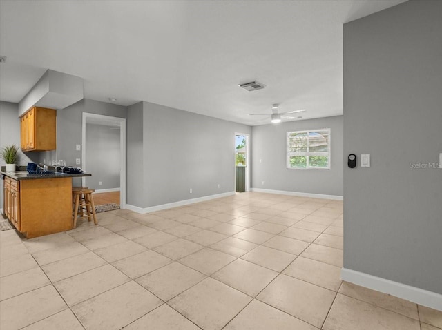 unfurnished living room with baseboards, visible vents, light tile patterned floors, and ceiling fan