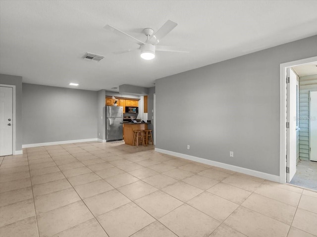 unfurnished living room with baseboards, visible vents, light tile patterned floors, and a ceiling fan
