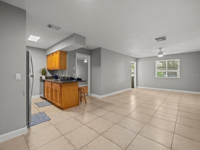 kitchen featuring light tile patterned floors, dark countertops, a ceiling fan, and open floor plan